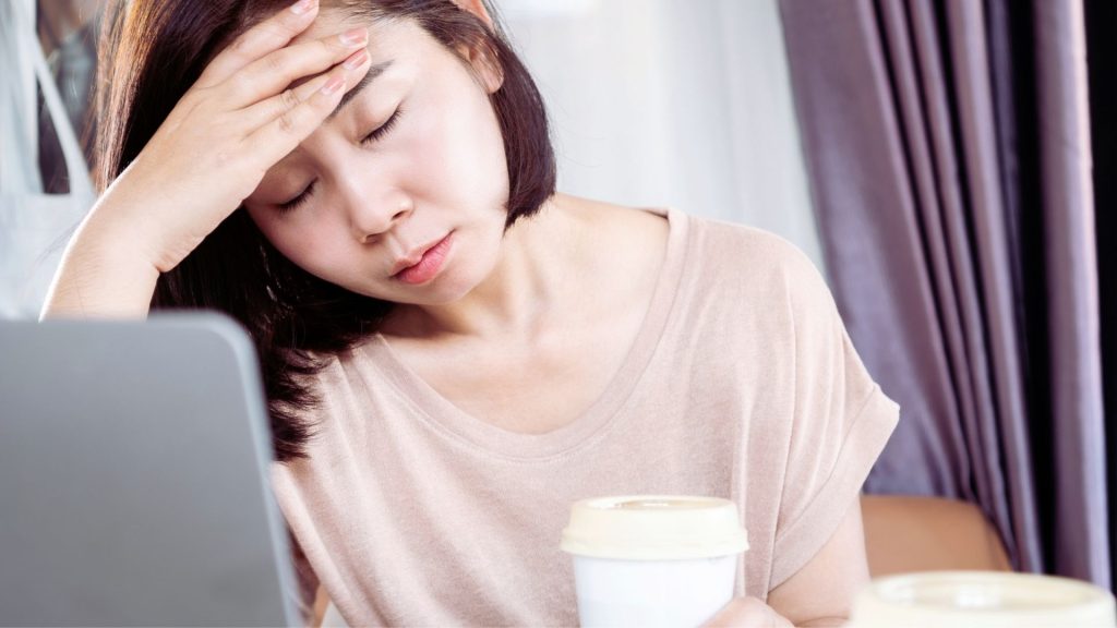 Woman experiencing headache and fatigue from Vivitrol side effects.