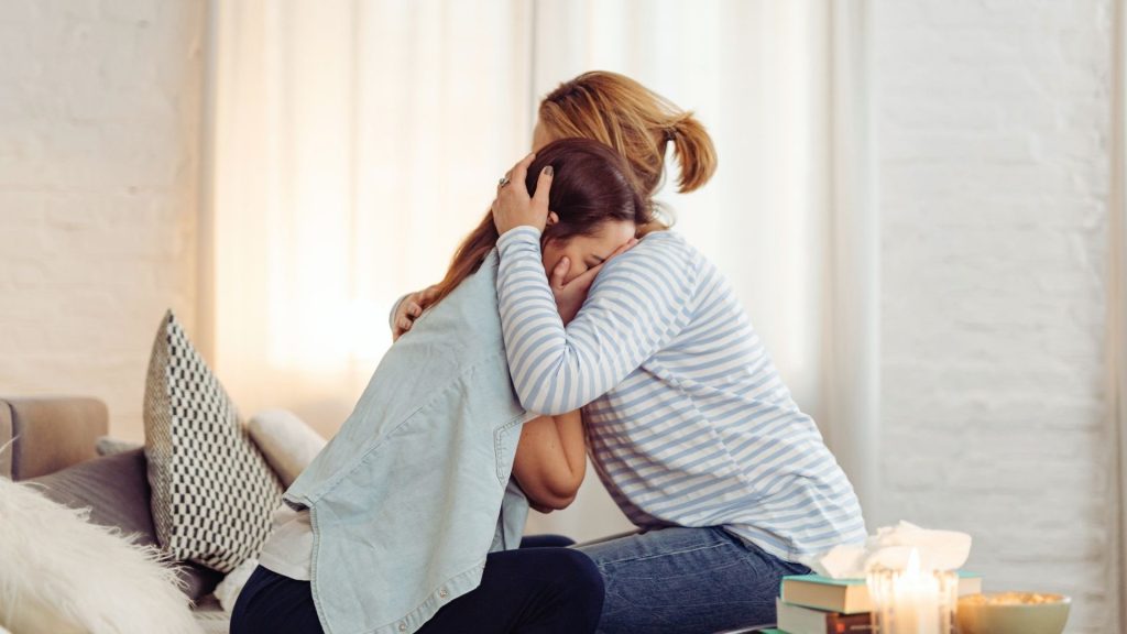 A loved one offering comfort to someone showing signs of emotional distress linked to addiction.