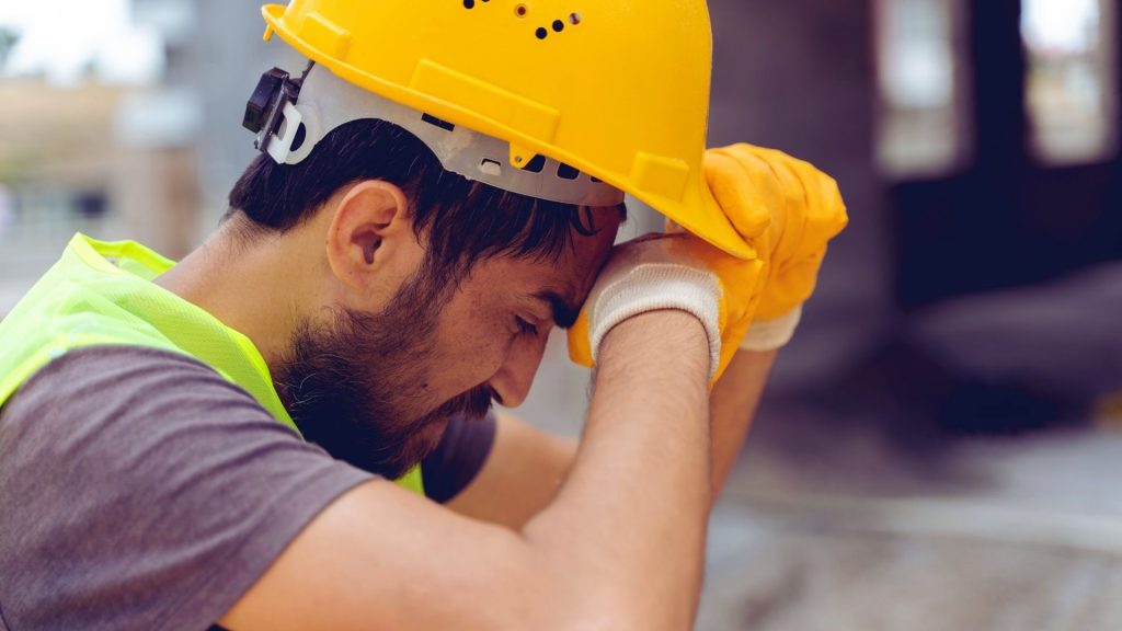 Worker pausing on a job site, showing physical and mental strain during recovery